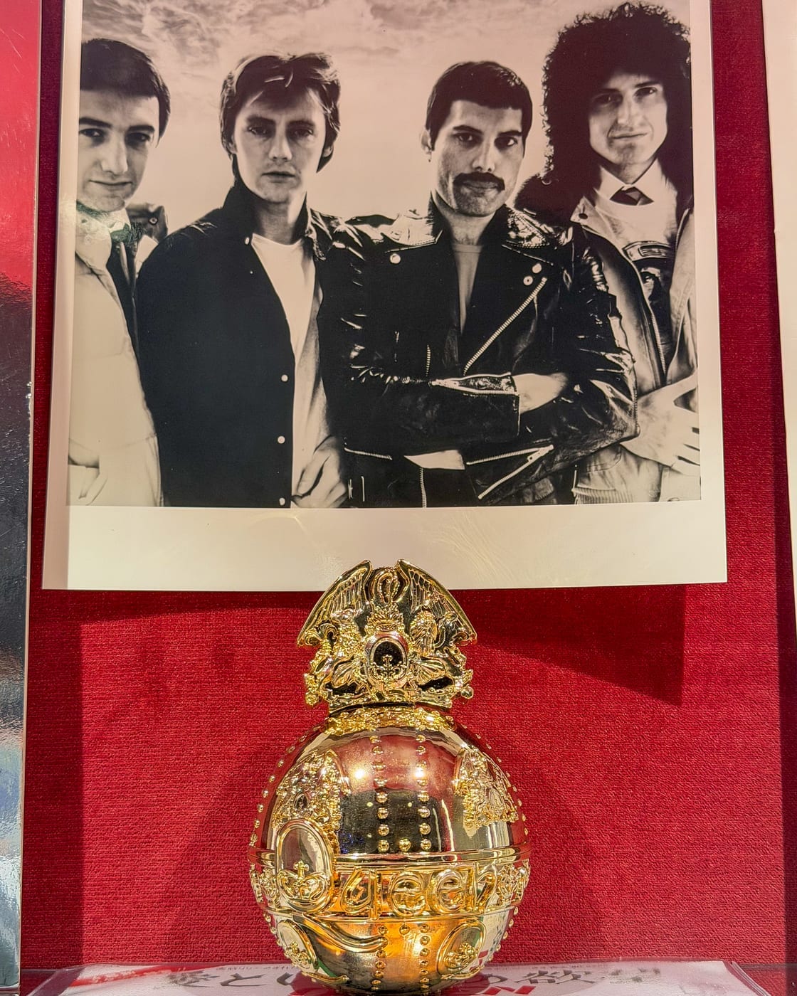 Une photo du groupe et un objet doré aux armoiries de Queen, le blason dessiné par Freddie Mercury.
